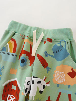 Light green cotton toddler shorts with farm animal print, rainbow, tractor, and watering can.