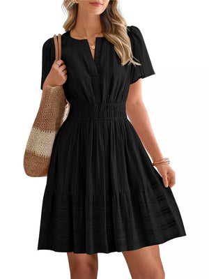 Black textured V-neck tiered dress with smocked waist and short puff sleeves.