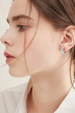 Silver moissanite channel-set hoop earrings sparkle on a woman's ear.