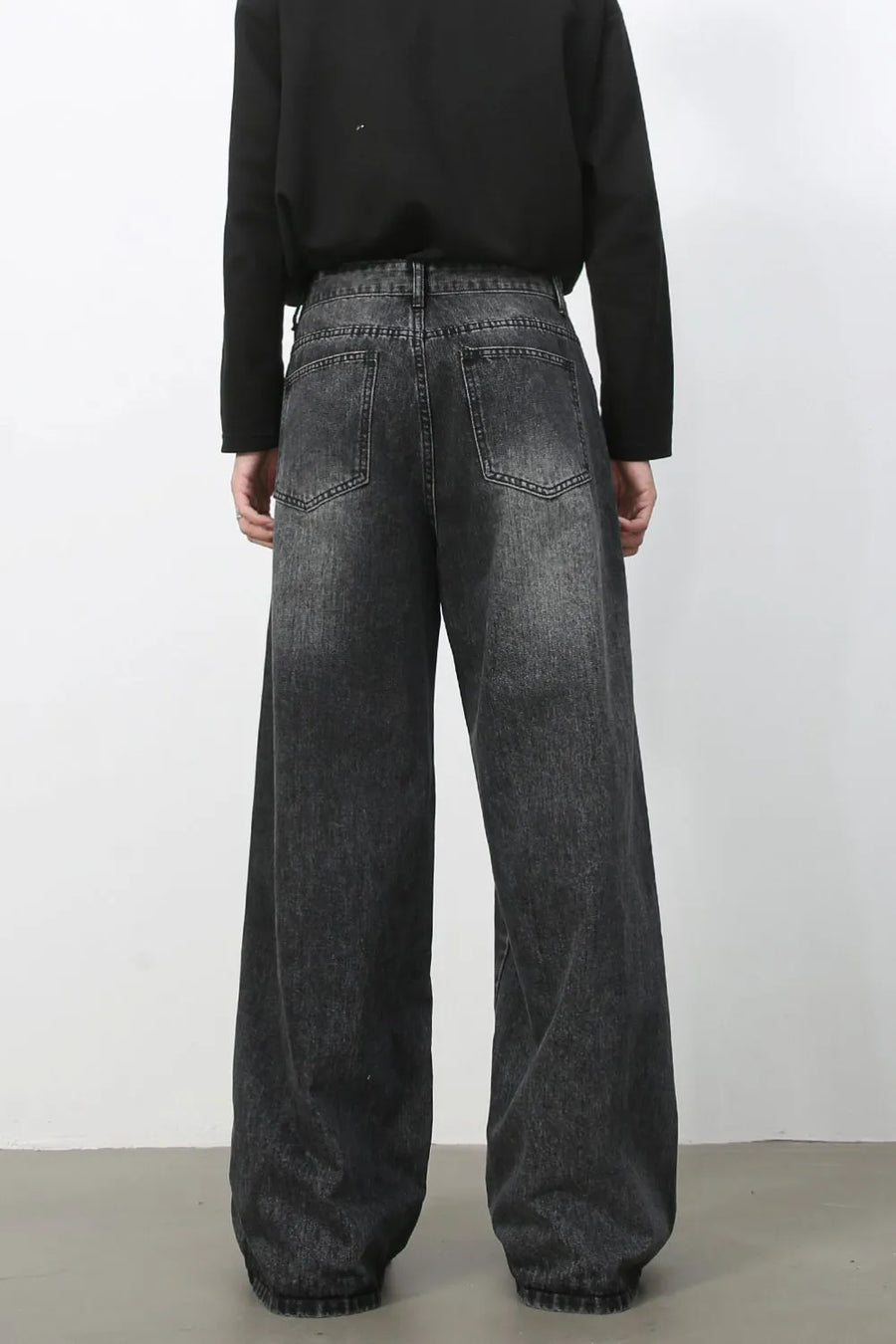 Exaggerated wide-leg dark wash denim trousers with a relaxed fit and distressed details.
