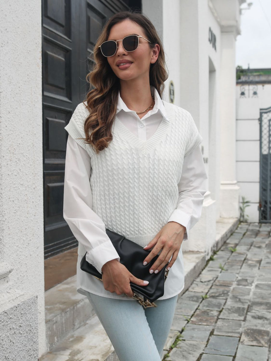 White cable knit V-neck sleeveless sweater over a white collared shirt.