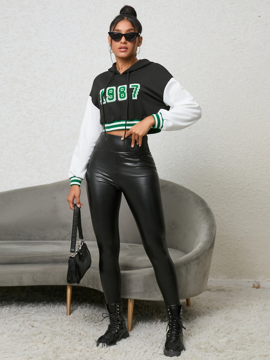 Black cropped hoodie with white sleeves and '87 graphic, featuring green trim.