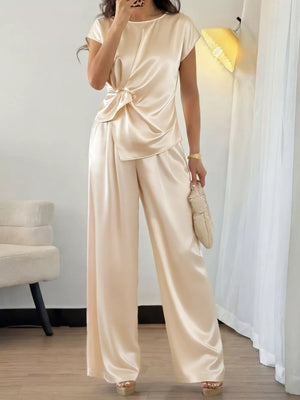 Champagne satin twist-front top with cap sleeves and flowing wide-leg pants.