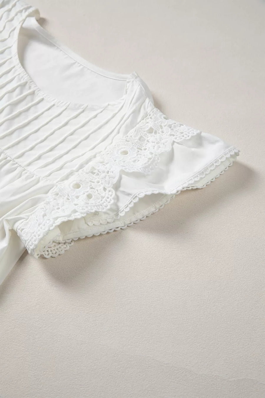 White cotton shirt with lace flutter sleeves and pleated front detail.