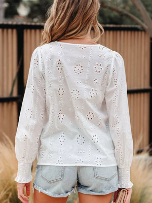 White cotton blouse with eyelet embroidery and ruffled cuffs.