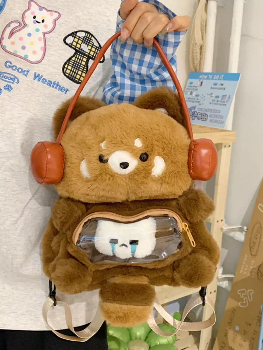 Caramel plush cat backpack with headphone detail and clear display pocket.