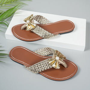 Gold bow embellished flat sandals with woven straps and brown footbed.