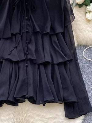 Black chiffon tiered blouse with ruffled details and bow-tie neckline.