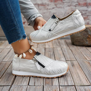 White zebra print slip-on flats with side zippers and black trim.