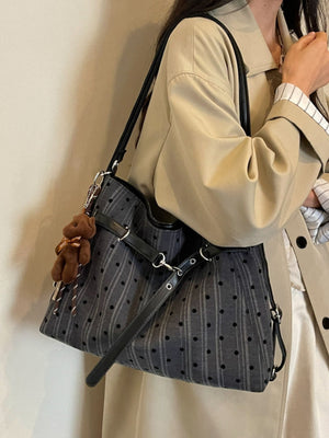 Black handbag featuring buckle straps and polka dot, striped