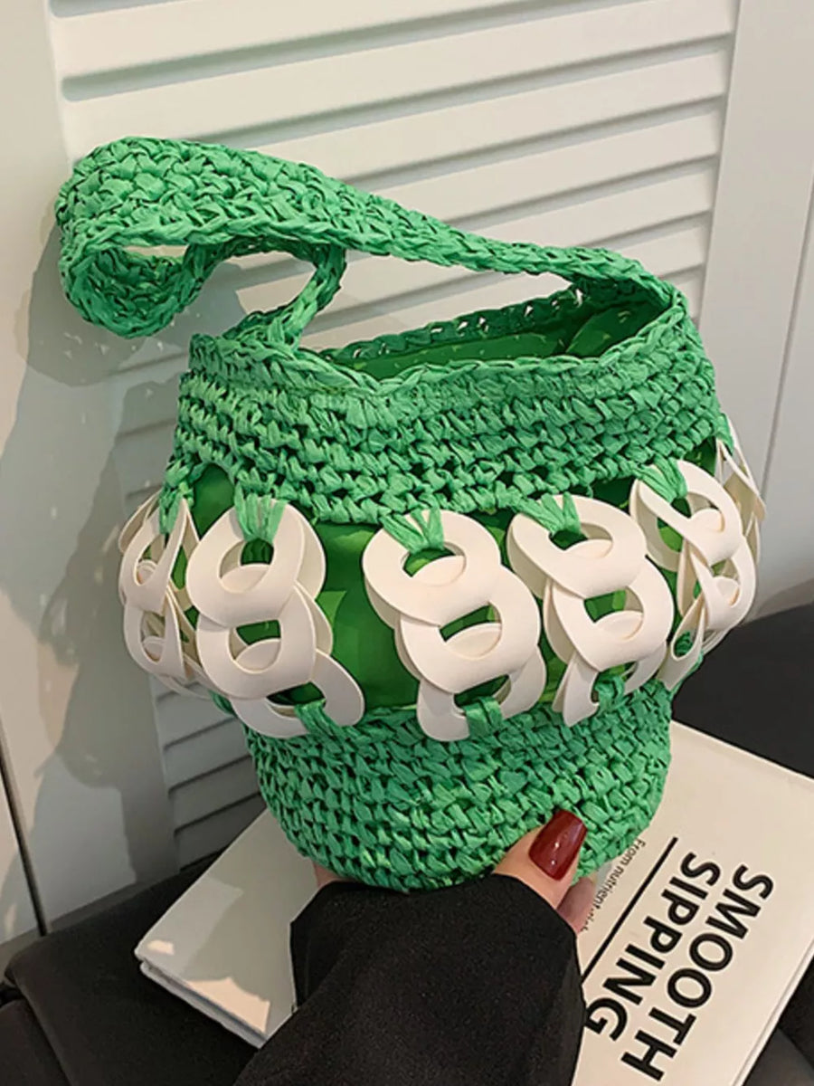 Green woven straw bucket tote with white chain detail and green lining.