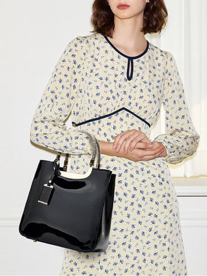 handbag in black featuring metallic handle and boxy fit