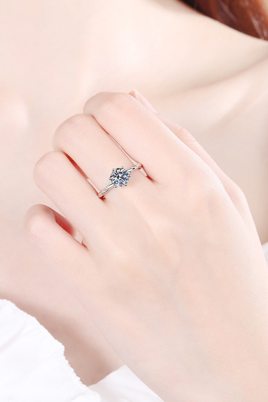 Silver moissanite solitaire ring with twisted band detail.
