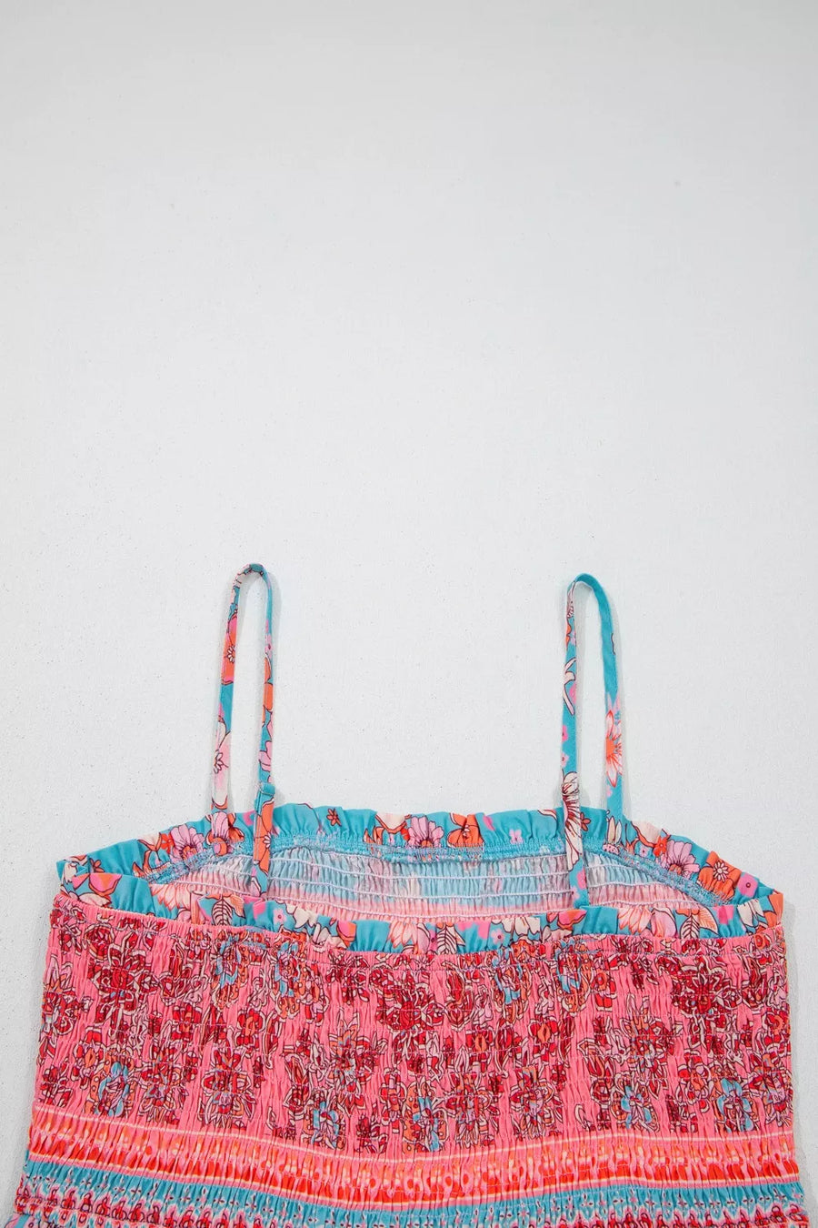 Bohemian floral maxi dress with smocked bodice, spaghetti straps, and vibrant pink, orange, and blue print.
