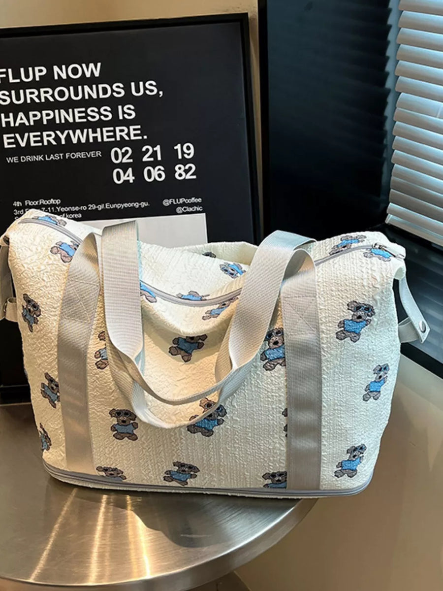Tote bag with teddy bear print, textured cream fabric, grey trim and handles.