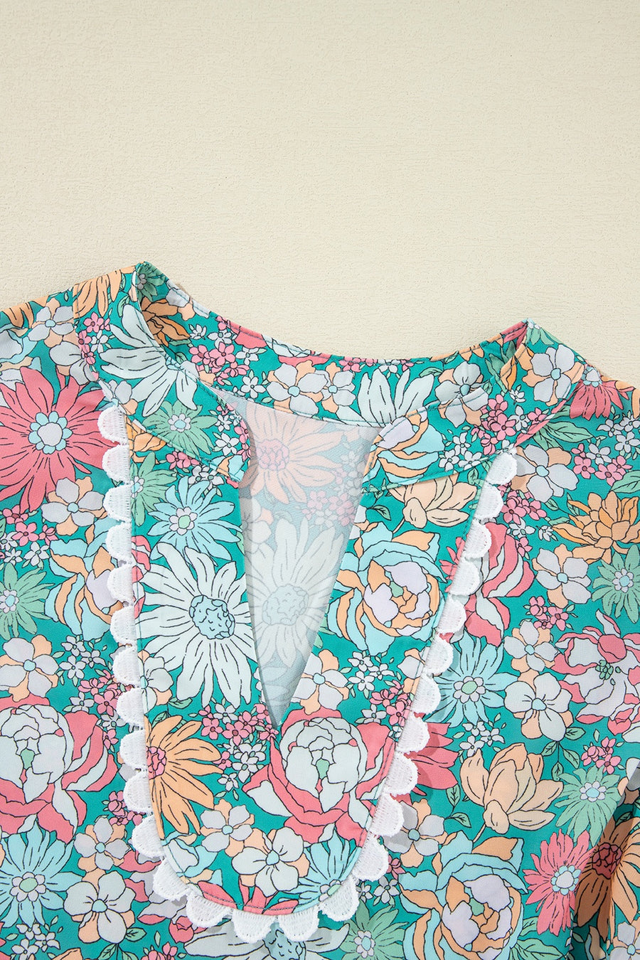 Floral peplum blouse with scallop trim and V-neckline.