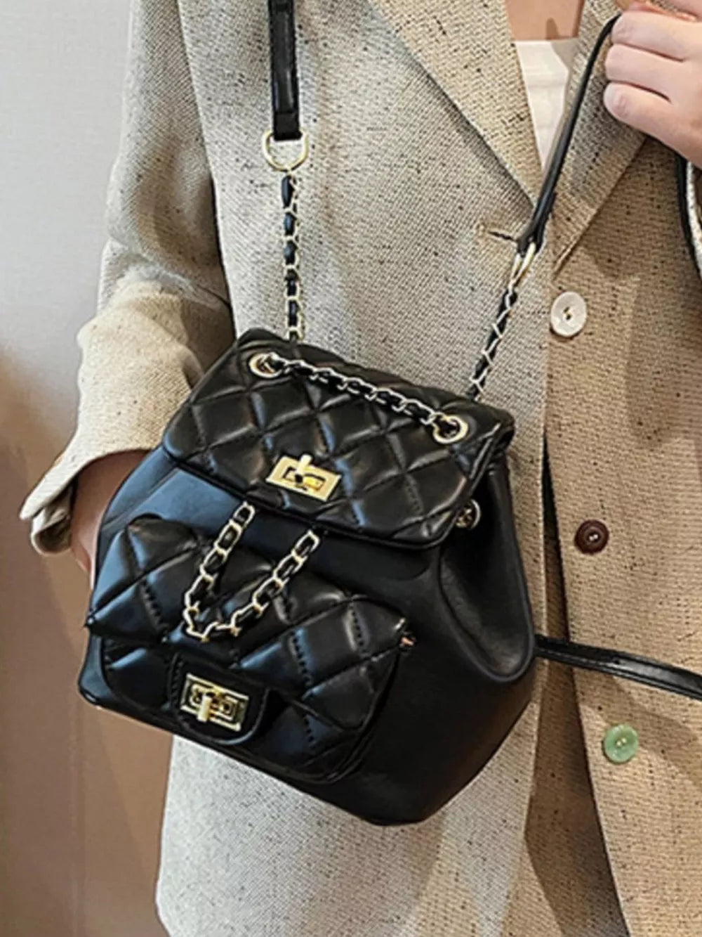 Black quilted mini backpack with gold chain straps and turn-lock closures.