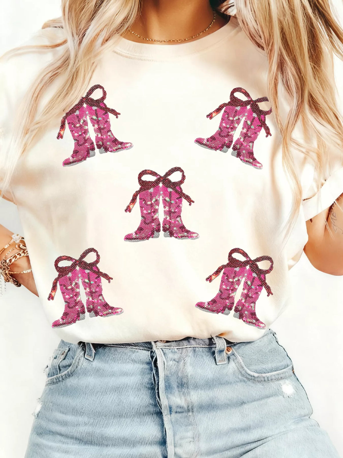White graphic tee with allover pink sequined cowgirl boots print and bow detail.