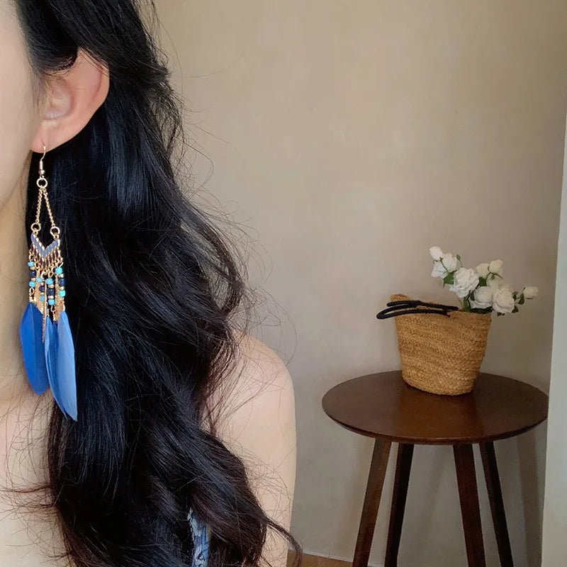 Blue feather drop earrings with beads and alloy accents.