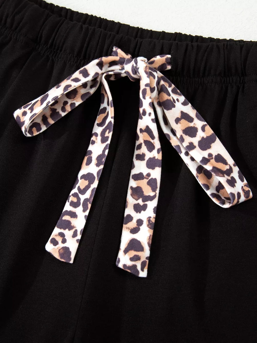 Black pajama shorts with leopard print tie detail and elastic waistband.