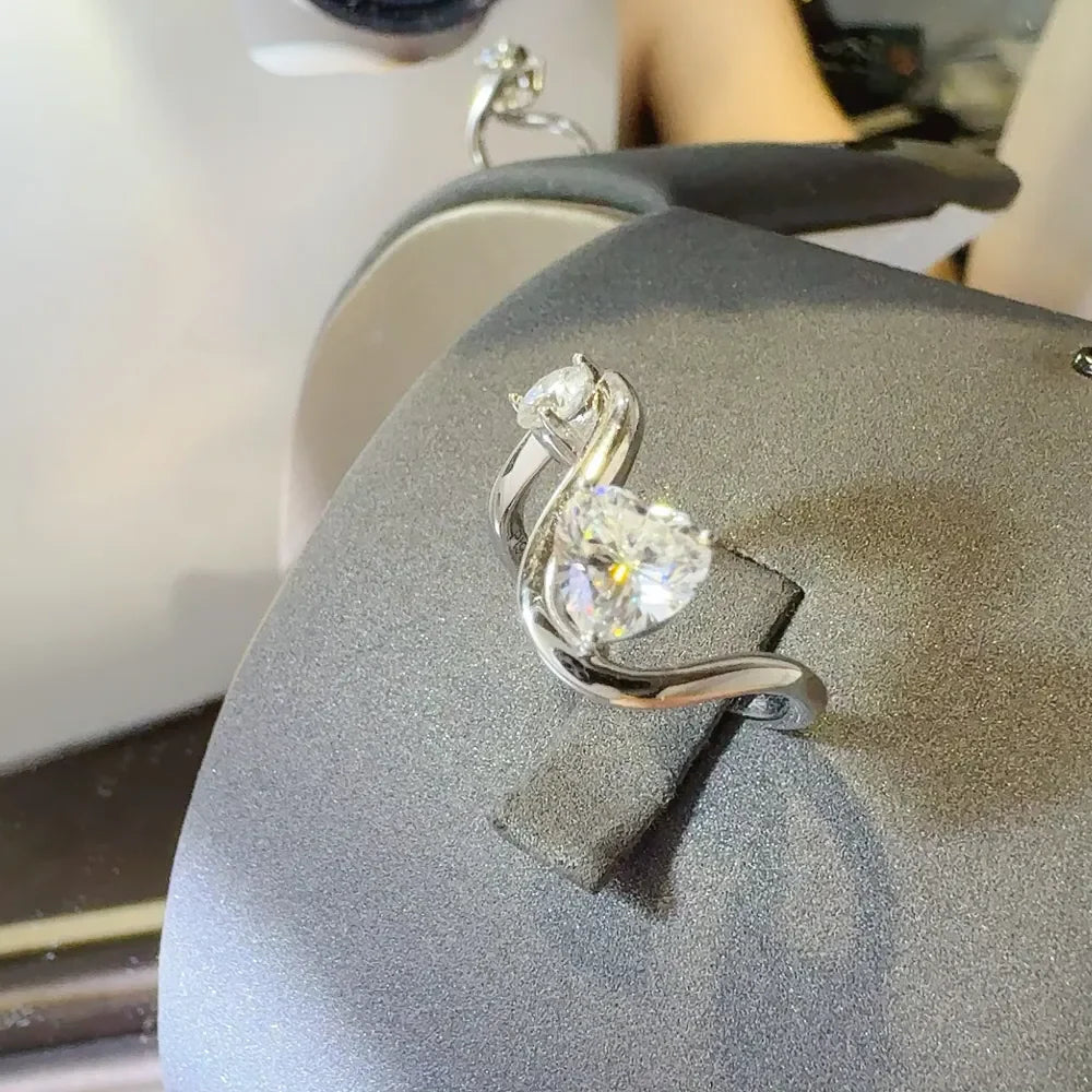 Silver heart-cut diamond infinity ring with two sparkling stones on a display stand.