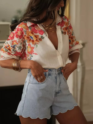 White linen shirt with floral embroidery, paired with light wash denim shorts with scalloped hem.