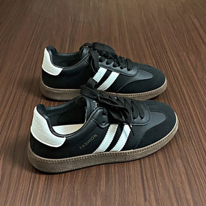 Black leather sneakers with white stripes and branding, casual court-inspired style.
