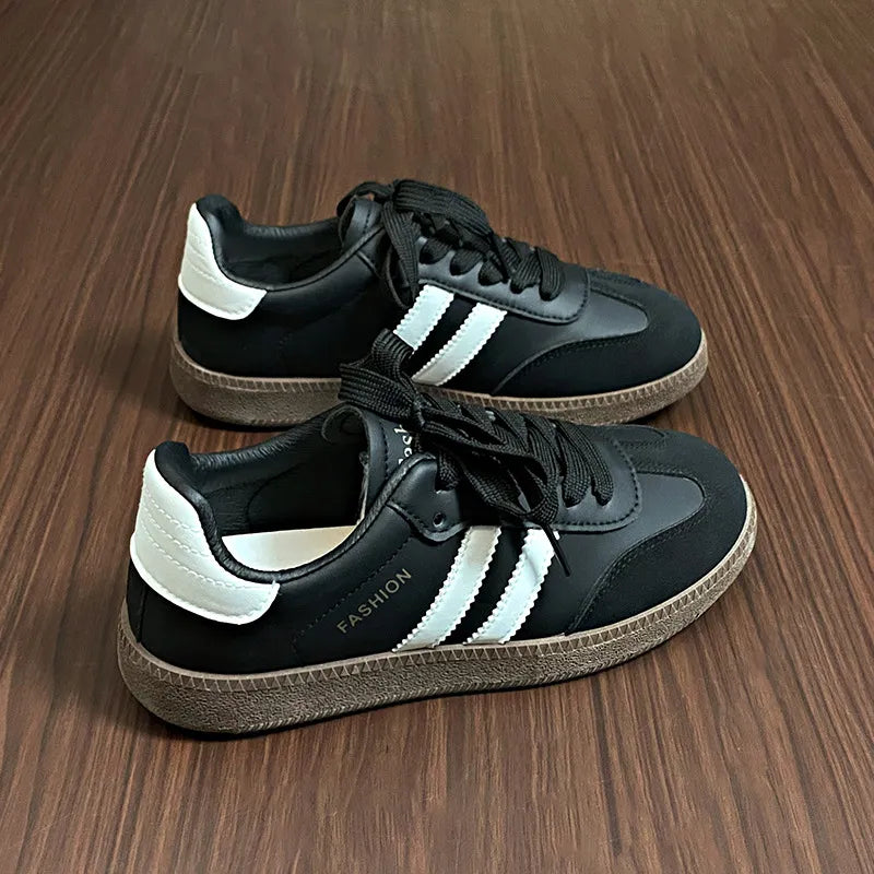 Black leather sneakers with white stripes and branding, casual court-inspired style.