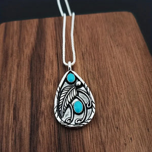 Silver pendant with turquoise stones and feather detail