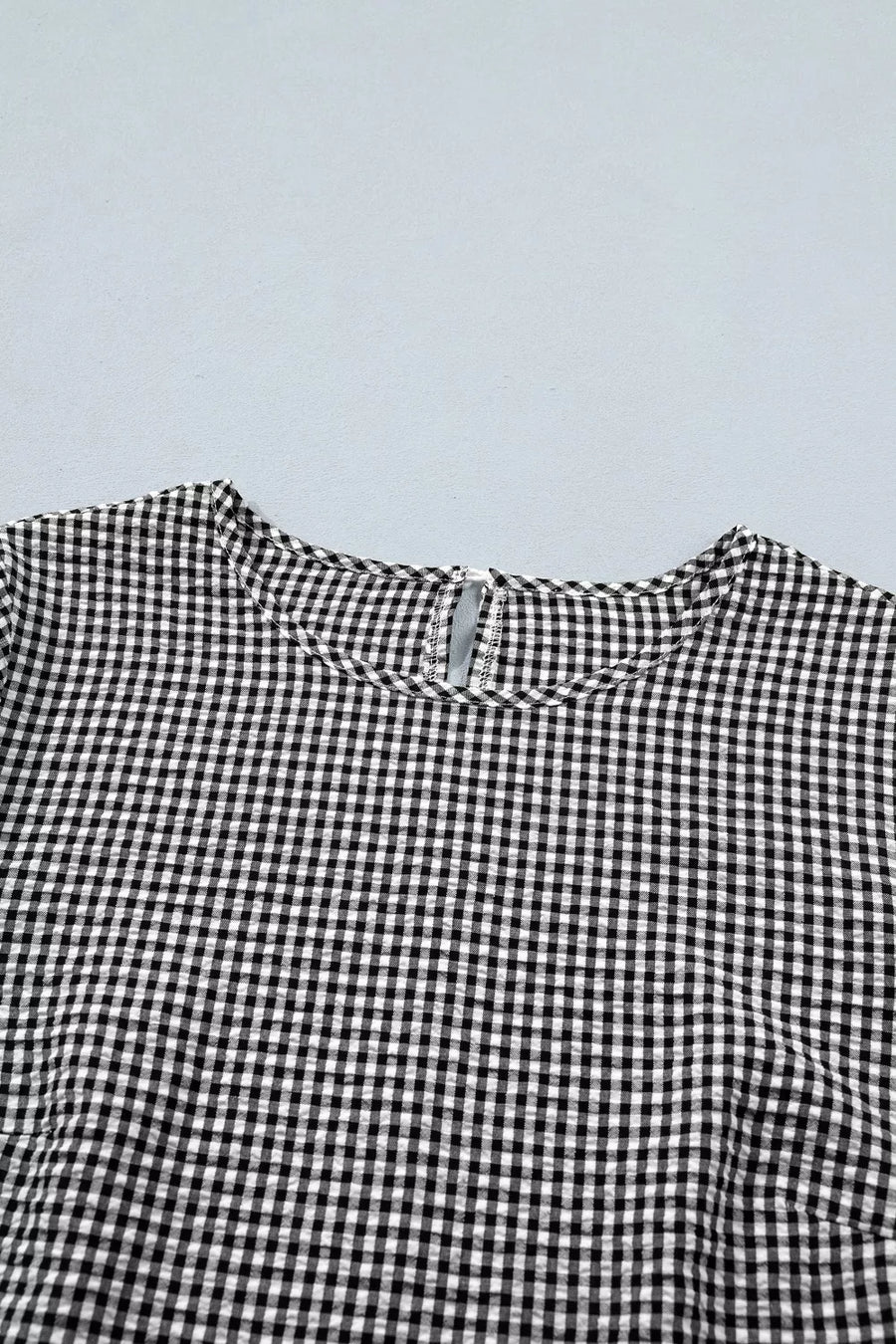 Black and white gingham polyester shirt with ruffled detail and keyhole back.