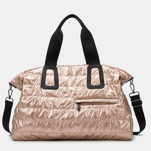 Glossy padded holdall bag in rose gold with black straps and a front zip pocket.