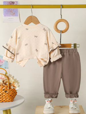 Baby girls tan outfit with bow print top and ruffled sleeves, paired with brown pants.