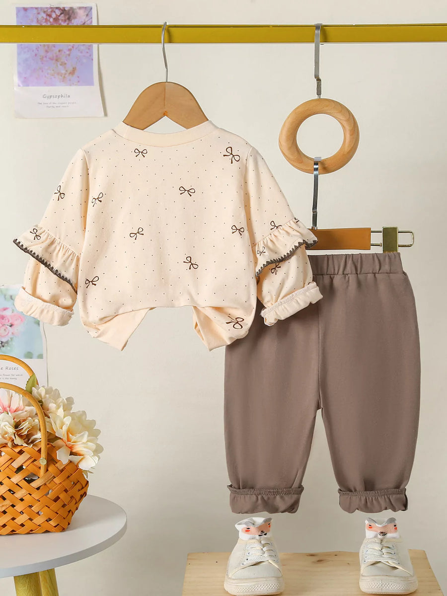 Baby girls tan outfit with bow print top and ruffled sleeves, paired with brown pants.
