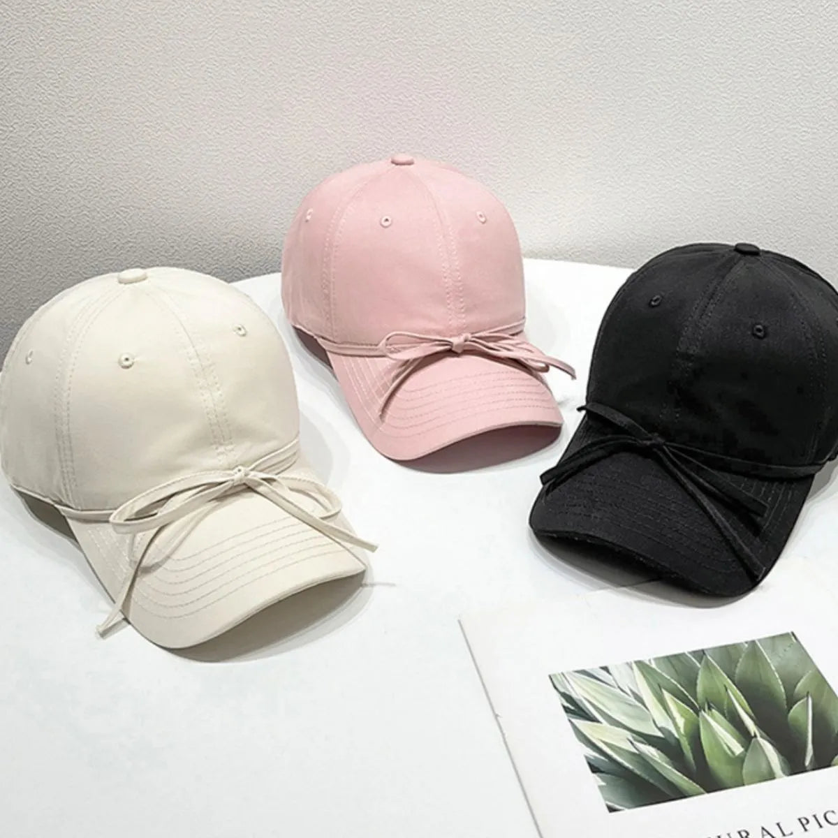 Baseball cap in blush pink, cream, and black with acrylic bow detail