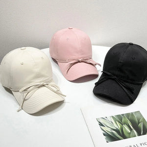 Baseball cap in blush pink, cream, and black with acrylic bow detail