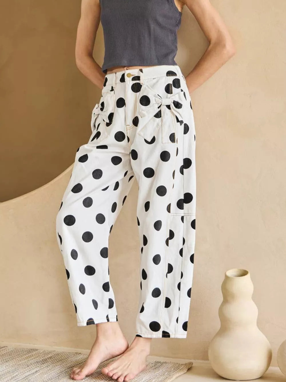 Polka dot high-waisted jeans in white denim with black dots and bow details on pockets.