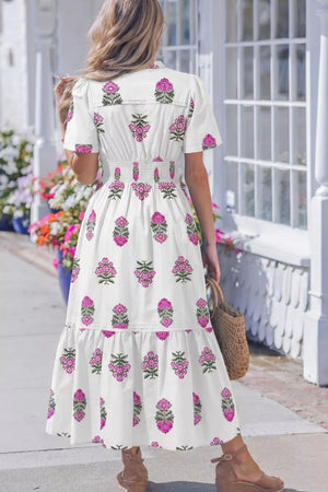 White cotton midi dress with pink floral print, V-neck, short sleeves, and smocked high waist.