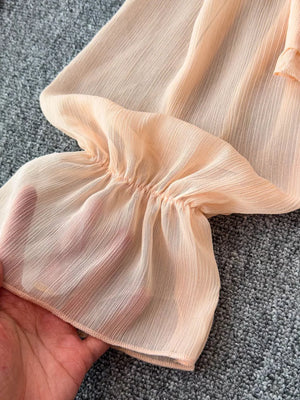Peach sheer maternity blouse with ruffled sleeve detail and gathered cuff.