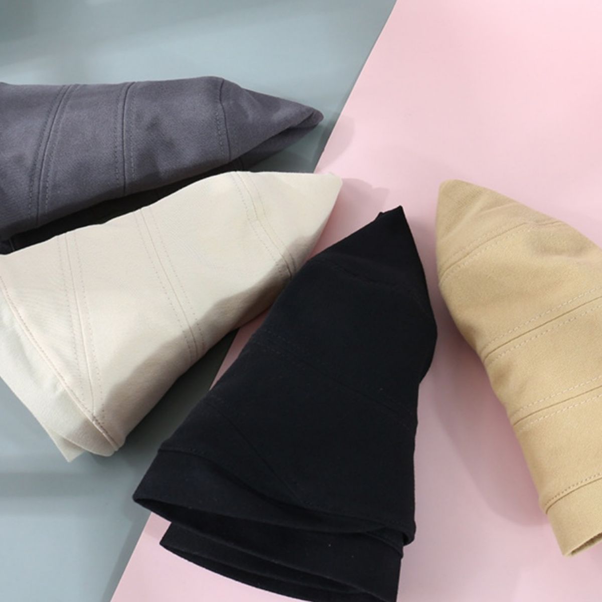 Cotton bucket hats in dark gray, ivory, black, and tan with stitched details.