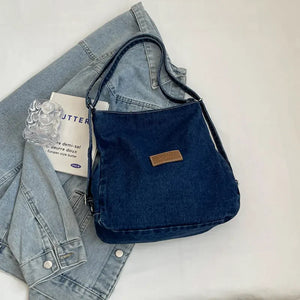 Denim hobo bag in medium blue with leatherette patch and adjustable strap.