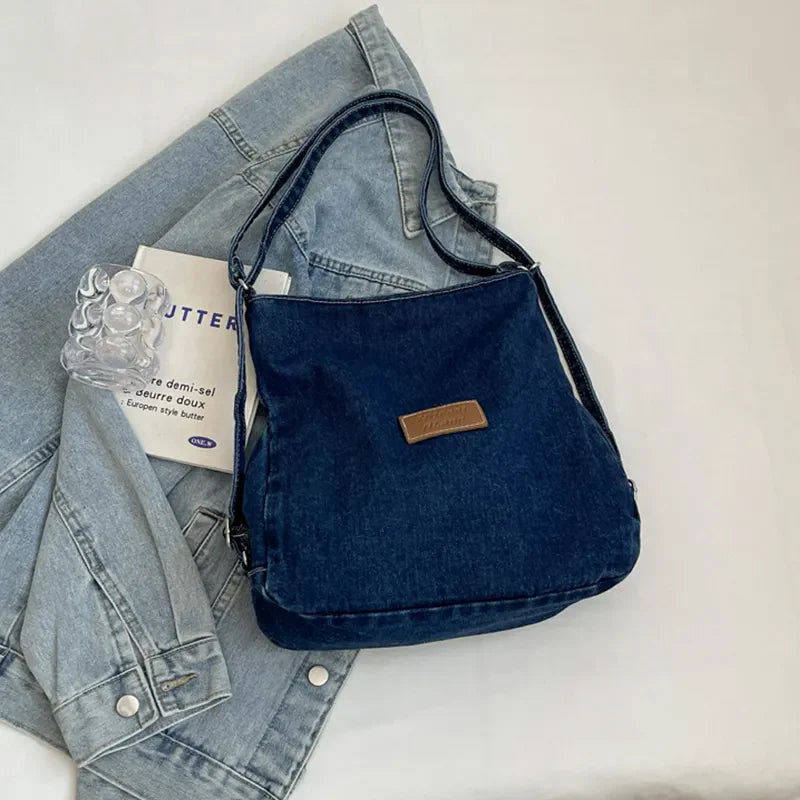 Denim hobo bag in medium blue with leatherette patch and adjustable strap.