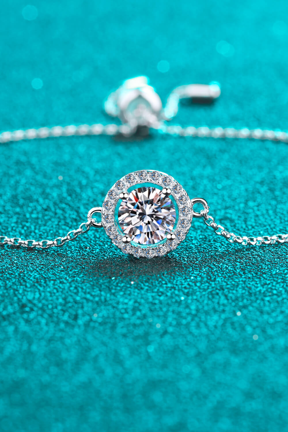 Silver adjustable bracelet with a round moissanite halo pendant.