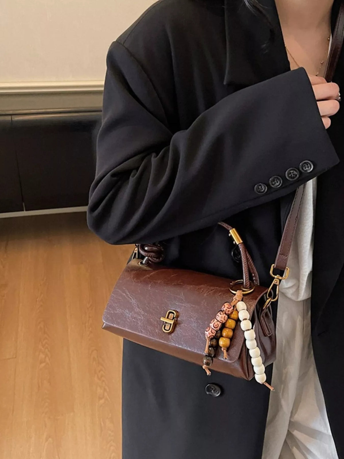 Brown leather crossbody bag with beaded charm and gold clasp