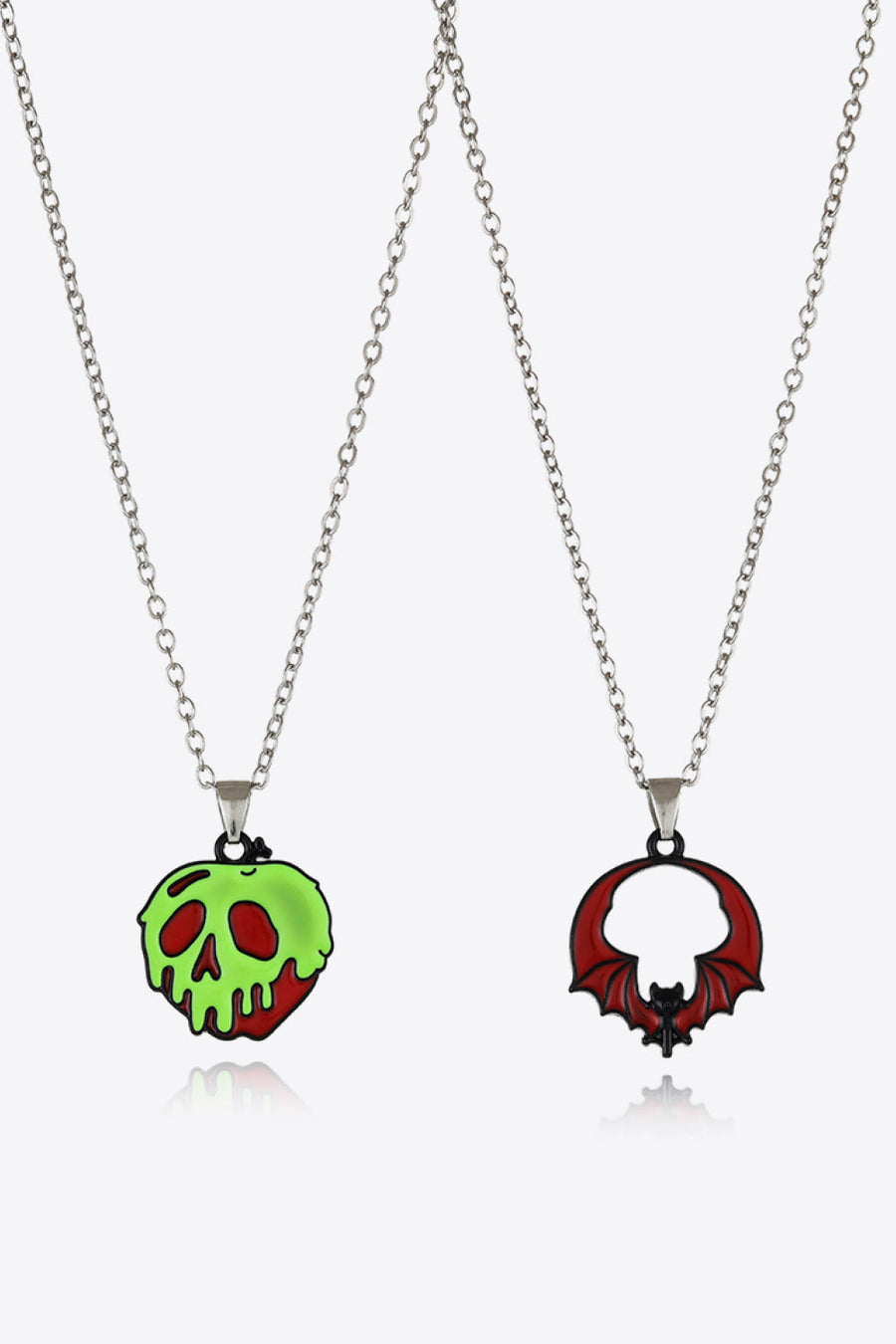 Spooky season enamel pendant necklaces, one green skull apple and one red bat.
