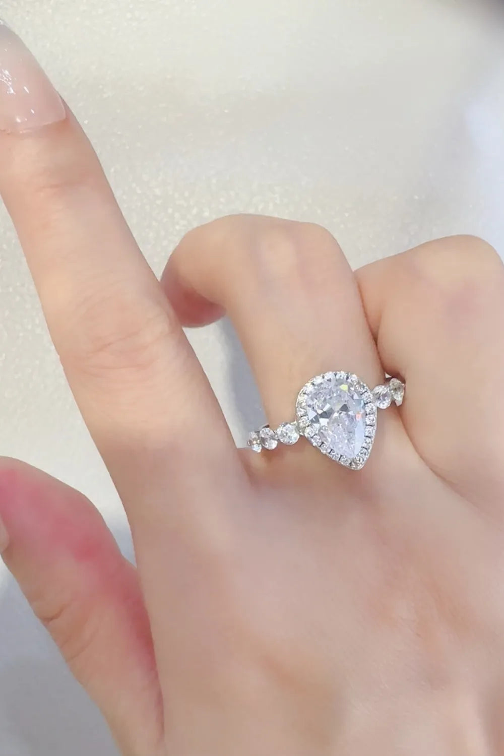 Silver pear-cut halo moissanite ring with accent stones on band