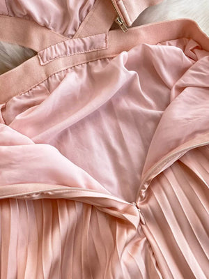 Pink pleated maxi dress with cutout detail and zipper closure.
