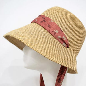 Straw sun hat with red floral ribbon and tie.
