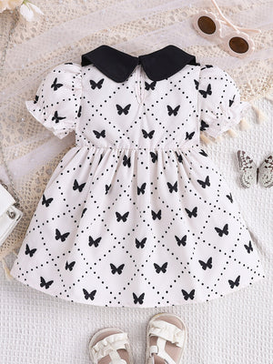 Baby dress with black collar, short puff sleeves, and allover black butterfly and dot print.