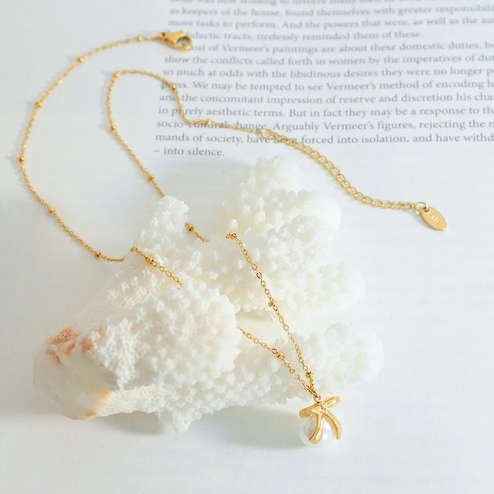 Gold bow-adorned pearl drop necklace with beaded chain detail