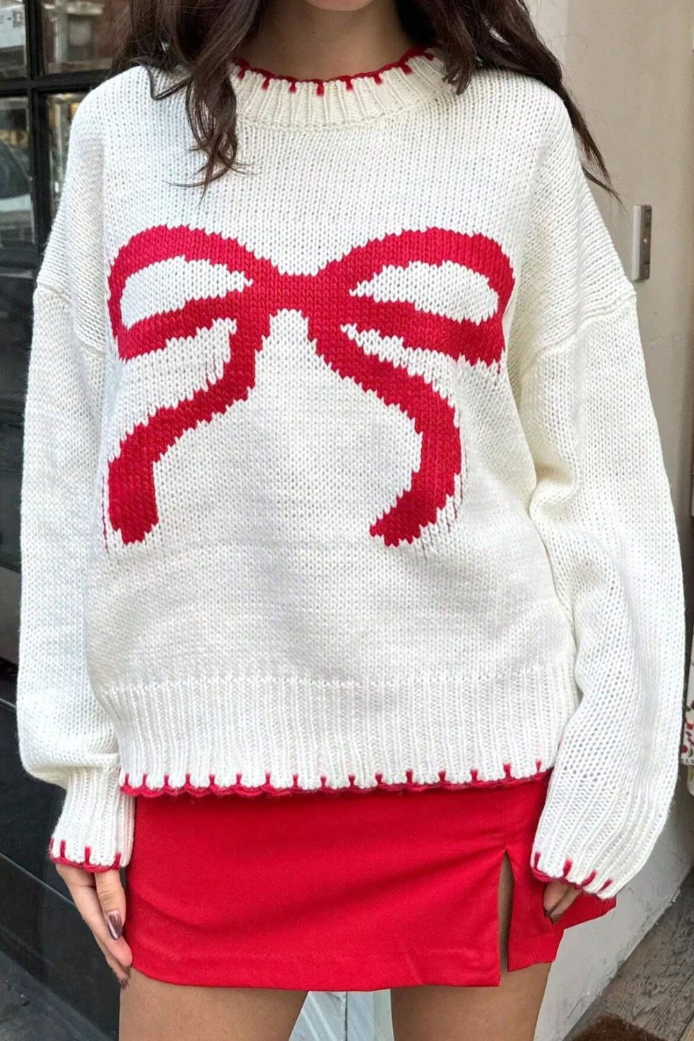 White acrylic knit sweater with red bow graphic and scalloped trim.